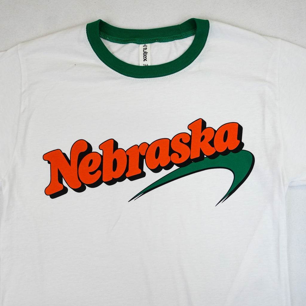 Close-up of bold orange Nebraska design and green swoosh on white ringer T-shirt