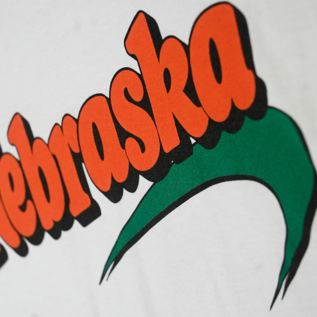 Close-up of orange Nebraska lettering and green swoosh screen print