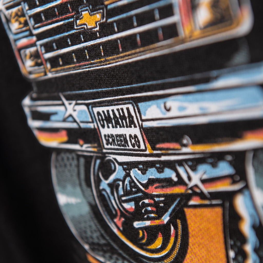Close-up of Omaha Screen Co van license plate detail on black tee